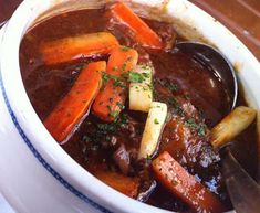 a white bowl filled with stew and carrots