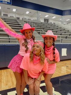 three girls dressed in pink posing for the camera with their arms around each other on a basketball court