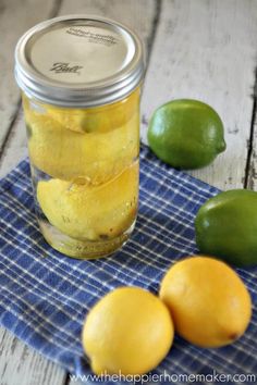 lemons and limes are sitting on a towel next to a jar of pickles