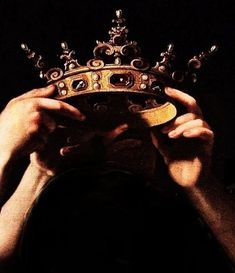 a person holding up a crown in front of their face