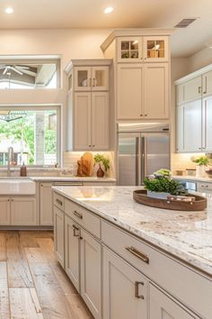 a large kitchen with white cabinets and marble counter tops, along with hardwood floorsing