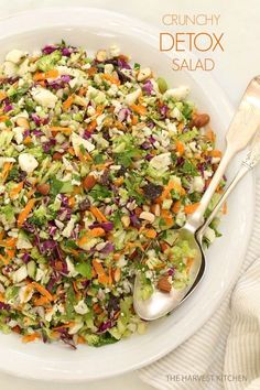 a salad with carrots, celery, lettuce and nuts in a white bowl