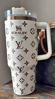 a white and brown cup sitting on top of a wooden table next to a purse