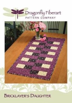 the dragonfly table runner is made with purple and black fabric, along with pink flowers