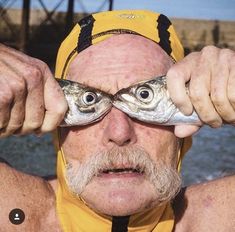 an older man holding up two fish in front of his eyes