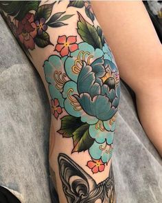 a woman's leg with flowers and a bat tattoo on her left calf area