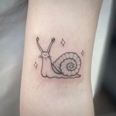 a small tattoo of a snail on the ankle, with stars around it and an arrow in the middle