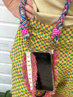 a person holding a cell phone in their pocket with some beads on it's belt