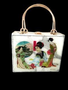 A very unusual handbag in a box shape with two gold top handles that features Japanese Geisha Artwork.  The print is created by the Designer as a pastiche of separate Ukiyo-e masterpieces. This artwork takes the centre stage on the bag at its front. The rest of the bag features a marble look grey/white subtle pattern in faux leather. The back of this luxury handbag has a textured 3D pattern in clear and metallic blue colours.  The inside of the bag is beautifully finished in fabric lining.  Stan Square Evening Bag, Gift Shoulder Bag With Top Carry Handle, Gift Rectangular Box Bag With Removable Pouch, Elegant Box Bag With Removable Pouch For Gift, Gift Box Bag With Removable Pouch In Rectangular Case, Vintage Rectangular Party Bag, Vintage Rectangular Box Bag For Party, White Rectangular Shoulder Bag Gift, Rectangular Box Bag With Top Carry Handle