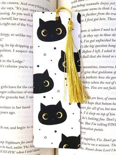 a bookmark with black cats on it and a tassel hanging from the end