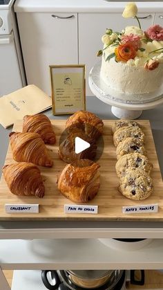 an assortment of baked goods displayed on a wooden cutting board in front of a cake