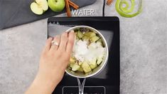 someone is cooking food in a pot on the stove top with an apple and cinnamon stick next to it