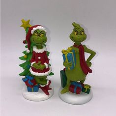 two green figurines are standing next to each other with presents in their hands