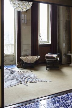 a room with blue and white flooring, chandelier and large windows in it