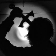 a man is holding a hammer in front of a light that reflects on the wall