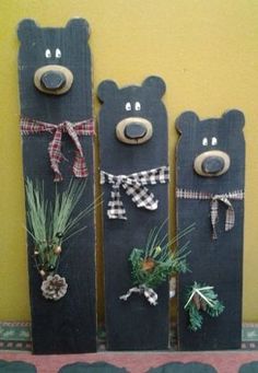 three wooden bears are decorated with pine cones and evergreen needles, tied to the sides