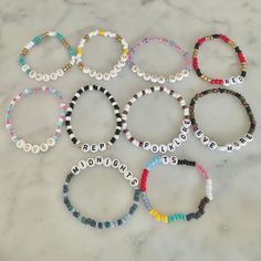 six personalized bracelets on a marble surface with the word hope spelled in small letters