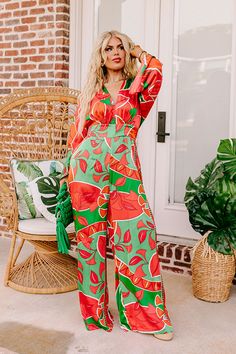 - This stunning jumpsuit is a ticket to sunshine vibes! Featuring a bold vibrant print and a chic satin finish, this trendy wide leg jumpsuit promises to steal the spotlight and keep you feeling fabulous. - Unlined material with a pink, orange, and green hued abstract botanical print with a satin finish - A v-cut neckline and a v-cut back with a tie detail - Long. loose sleeves - A waistline with an elastic back and an attached tie closure belt - A relaxed silhouette that ends in wide hemlines Trendy Wide-leg Jumpsuits And Rompers For Vacation, Trendy Wide Leg Jumpsuits And Rompers For Vacation, Trendy Wide-leg Jumpsuits For Vacation, Chic Orange Jumpsuits And Rompers For Vacation, Chic Orange Jumpsuit And Romper For Vacation, Multicolor Wide Leg Jumpsuits And Rompers For Summer, Wide Leg Multicolor Jumpsuits For Summer, Wide Leg Multicolor Jumpsuits And Rompers For Summer, Chic Printed Jumpsuits And Rompers For Brunch