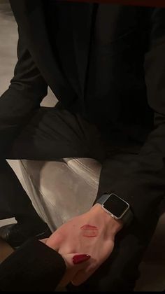 a person in a suit and red nail polish holding an apple watch