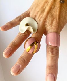 a woman's hand with pink and gold manicures holding a ring on her finger