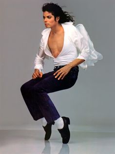 a man in white shirt and black pants doing a dance move with his legs spread out