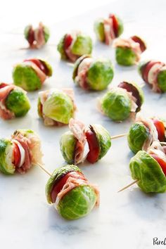 some food is laying out on a white table and it looks like they have been wrapped in bacon or lettuce