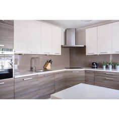 a kitchen with white cabinets and gray counter tops, along with a wooden cutting board on the counter