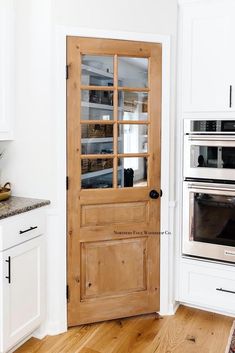 a kitchen with an oven, microwave and wooden door