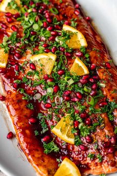 salmon covered in pomegranate and garnished with lemons, parsley and herbs