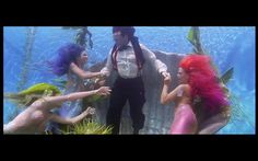 three mermaids are dancing in front of a man