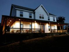 a large house lit up at night with lights on the porch and covered patio area