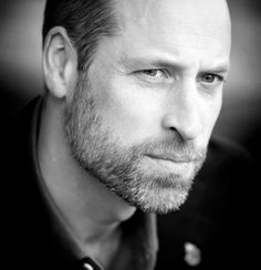 a black and white photo of a man with a goatee looking at the camera