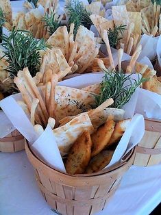 several baskets filled with different types of food on top of a white tablecloth covered table