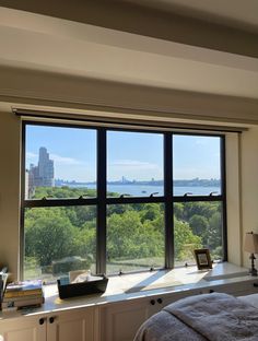 a bedroom with a large window looking out onto the trees and city skylines in the distance