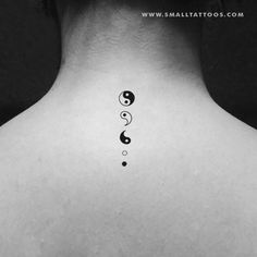 a black and white photo of a woman's back neck with two symbols on it