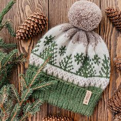 a green and white knitted hat next to pine cones