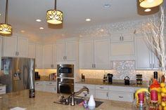 a large kitchen with white cabinets and stainless steel appliances, along with marble counter tops