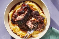 a bowl filled with meat and mashed potatoes on top of a blue table cloth