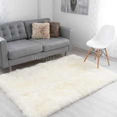 a living room with a gray couch and white chair next to a rug on the floor