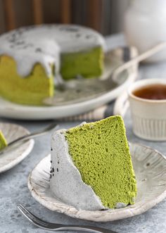 a piece of green cake on a plate with a fork and cup next to it