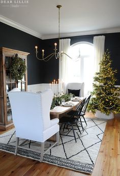 the dining room is decorated for christmas with black walls and white chairs, a chandelier