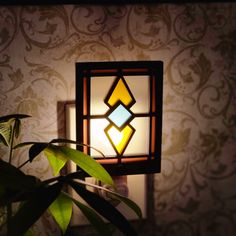 a light that is on the side of a wall next to a potted plant