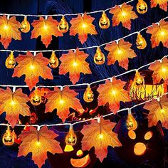 lighted pumpkins and leaves are hanging on a string