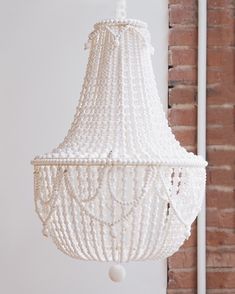 a white chandelier hanging from a brick wall