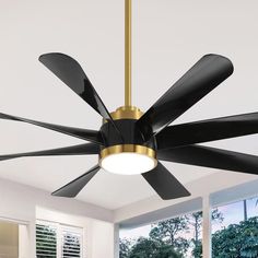 a ceiling fan that is hanging from the ceiling in a room with white walls and windows