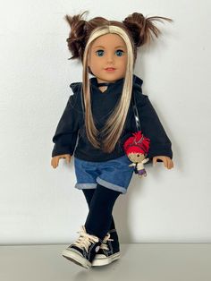 a doll with blonde hair and blue eyes sitting on top of a table next to a white wall