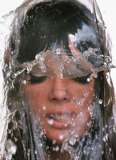 a woman is covered in water with her eyes closed and head tilted to the side