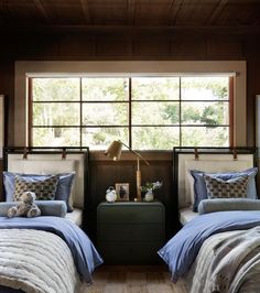 two beds in a bedroom with blue comforters and pillows on top of each bed