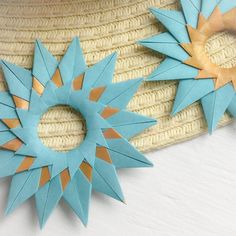 two blue and gold star brooches sitting on top of a straw hat next to each other