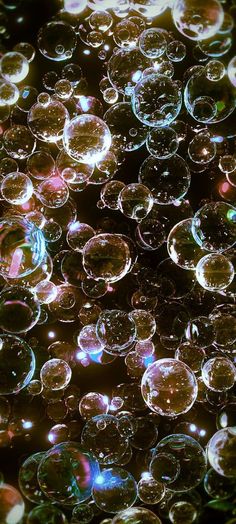 many bubbles are floating in the air on top of each other, with light reflecting off them